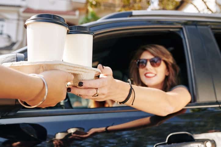 Waiter giving coffee cups to female driver